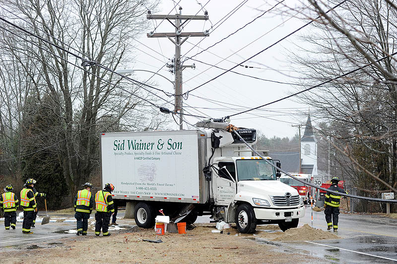 Falmouth firefighters contain a fuel spill on Route 9 in Falmouth Saturday by spreading sand. A box truck skidded off the road and slammed into a utility pole, cutting it in half.