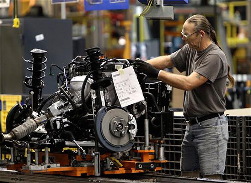 In this Dec. 14, 2011 photo, a line worker assembles an engine for a Ford Focus at the Ford Michigan Assembly plant in Wayne, Mich. The number of people applying for unemployment benefits dropped to its lowest level since April 2008, continuing a downward trend that reflects a strengthening job market. (AP Photo/Paul Sancya)