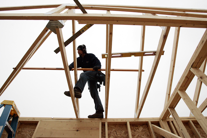 A worker sets a roof truss on a home under construction in LaPorte, Ind., recently.