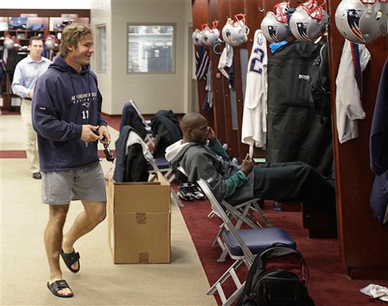 New England Patriots wide receiver Julian Edelman walks through the locker room past Chad Ochocinco, sitting in front of his locker, during a media availability at the NFL football team's facility in Foxborough, Mass., Wednesday morning, Nov. 30, 2011. (AP Photo/Stephan Savoia)
