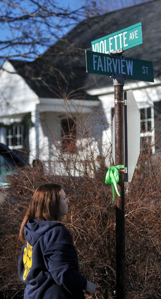 Brandi Wentzel, of Fairfield, hangs a green ribbon on a street sign at the intersection of Fairview Street and Violette Avenue near the home of missing 20-month-old Ayla Reynolds on Thursday.