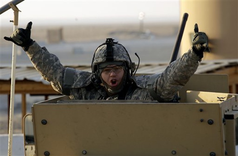 A soldier gestures from the gun turret of the last vehicle in a convoy of the US Army's 3rd Brigade, 1st Cavalry Division crosses the border from Iraq into Kuwait, Sunday, Dec. 18, 2011. The brigade's special troops battalion are the last American soldiers to leave Iraq. (AP Photo/Maya Alleruzzo)