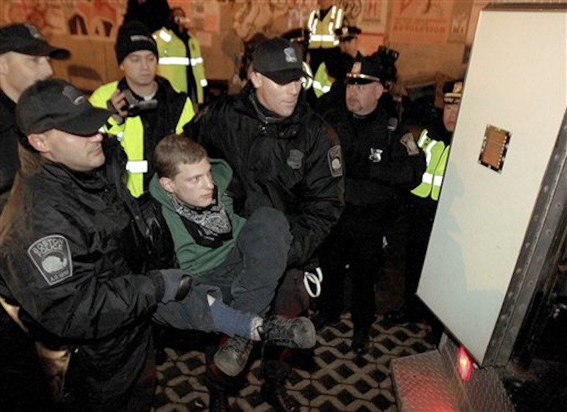 Boston police officers escort an Occupy Boston protester to a police van at Dewey Square in Boston before dawn Saturday, Dec. 10, 2011. More than 40 people were peacefully arrested as the park was cleared. The city had set a Thursday midnight deadline for protesters to leave or face eviction. (AP Photo/The Boston Globe, Essdras M Suarez, , Pool)