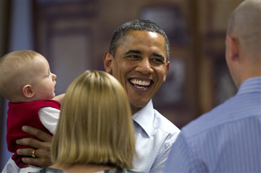 President Barack Obama laughs after getting a mouth full of fingers from Cooper Wall Wagner, 8 months, as he chats with Cooper's parents Captain Greg and Meredith Wagner, as he visits members of the military during Christmas dinner at Anderson Hall on Marine Corps Base Hawaii , Sunday, Dec. 25, 2011, in Kaneohe, Hawaii. (AP Photo/Carolyn Kaster)