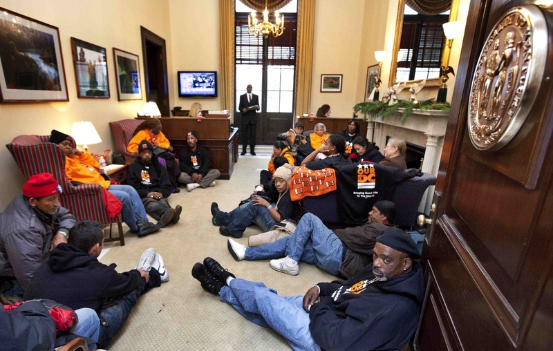 Keith Thomas, 49, right, and Orlando Gonzales, 88, left, in red hat, both from Washington, join in a protest inside the office of Senate Minority Leader Mitch McConnell, R-Ky., on Tuesday, the first day of a three-day protest event sponsored by a coalition of progressive organizations.