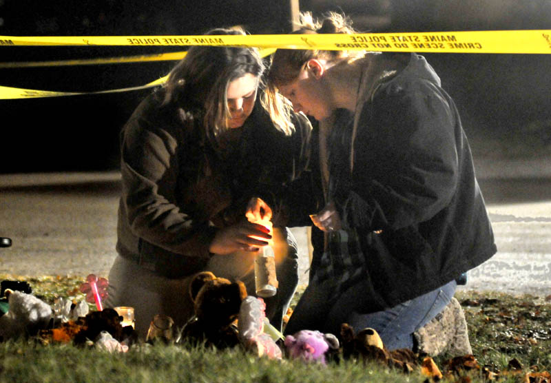 Staff photo by Michael G. Seamans Heather Mirucki, left, and Ashley Tenney, right, lights candles at a teddy bear shrine in front of the home of missing toddler, Ayla Reynolds, on Violette Avenue in Waterville Thursday night. Reynolds was reported missing Saturday.