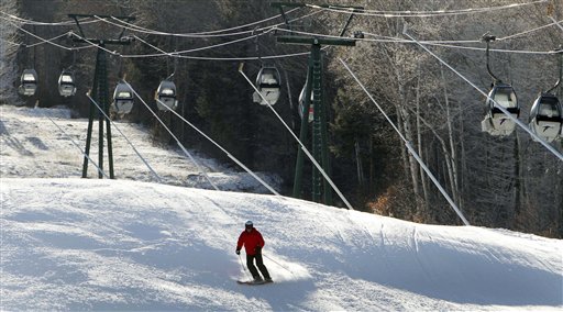 In this photo taken Monday Dec. 12, 2011, empty gondolas sit parked above a lone skier on an open trail at Loon Mountain ski area in Lincoln, N.H. Warm temperatures have continued to hover above optimal snowmaking levels, making for a late start to the ski season in the Northeast. (AP Photo/Jim Cole)