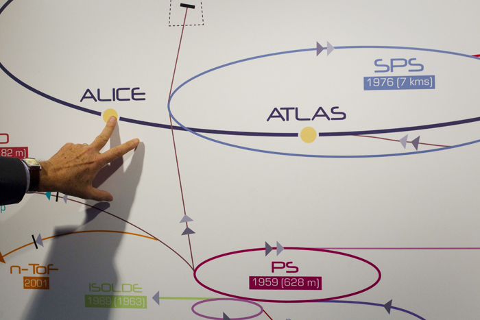 In this May 20, 2011, photo a physicist explains the Atlas experiment on a board at the European Center for Nuclear Research, CERN, outside Geneva, Switzerland. The illustration shows what a Higgs boson may look like in Atlas.