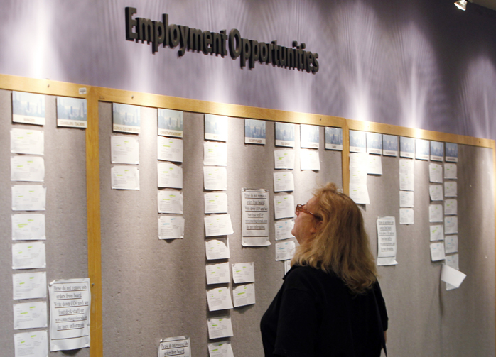 A woman looks at posted employment opportunities at a Denver employment office.