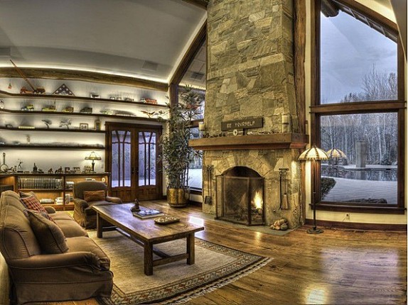 Actor Bruce Willis' Idaho home is marked by rustic stone and wood details, including two fireplaces in the living room area.