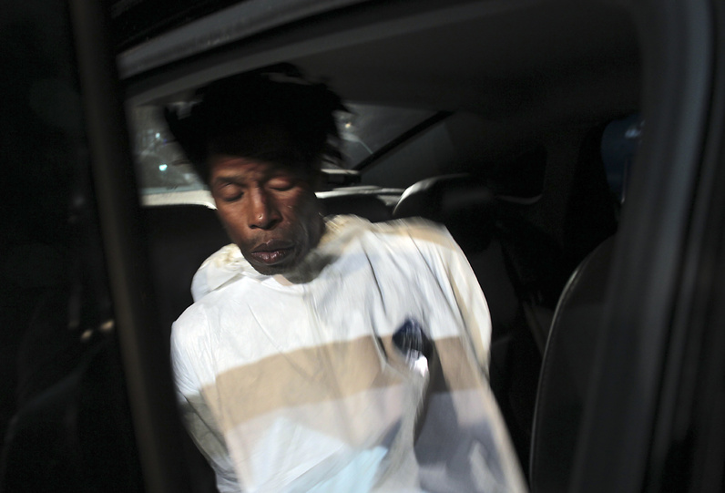 Jerome Isaac sits in a police car after being led out of the 77th Precinct in Brooklyn, N.Y., on Sunday, following his arrest in the death of 73-year-old Deloris Gillespie. Isaac told police he set Gillespie on fire in an elevator because she owed him $2,000, authorities said Sunday.