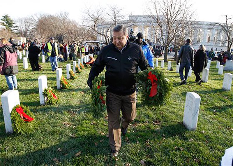 Maine Gov. Paul LePage prepares to place holiday wreaths at the grave of a fallen service member at Arlington National Cemetery during Wreaths Across America Day today.