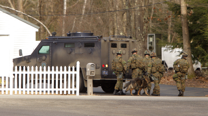 A SWAT team waits behind their vehicle at a house on New Dam Road in Sanford this morning. Police questioned some of fugitive David Hobson's relatives who live along the road and searched an area nearby where they found clothing and medical supplies.