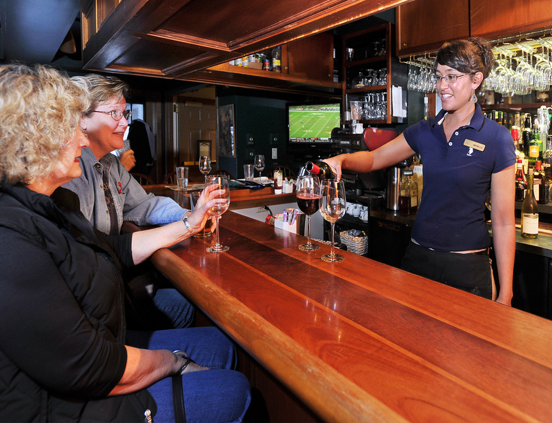 Barb Palmer, left, and Gayle Mooney, both from South Dakota and in Maine visiting relatives, watch as bartender Michelle Alexander pours a glass of wine at the Broad Arrow Tavern, located inside the Harraseeket Inn in Freeport.