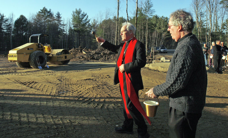 Bishop Richard Malone sprinkles holy water at the site of a new Roman Catholic church in South Berwick on Wednesday. At right is the Rev. Joseph Cahill, the parochial vicar for the parish.