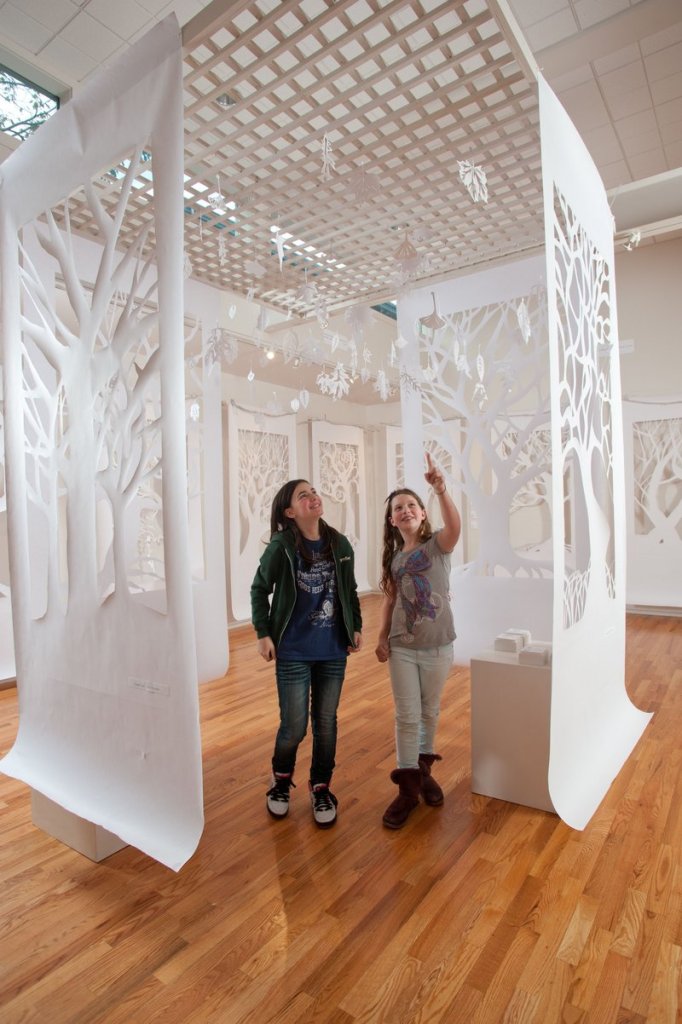 Fifth-graders Meredith Connor and Annabel Huber admire “Arboretum,” created by Waynflete School eighth-graders and hanging in the school’s Art Gallery.