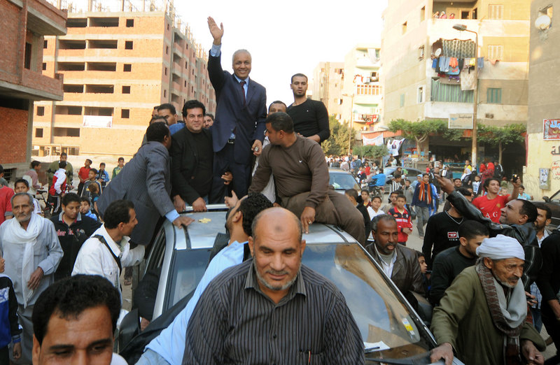 Supporters of Mustafa Bakri center, surround his car as they celebrate after he won a seat in the first round in South Cairo’s Helwan district, Egypt, Thursday.