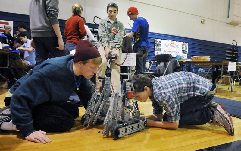 Harry Munroe, left, and Braden Becker, right, inspect their team’s robot as teammate Carter Hall, center, operates the controls before the Yarmouth team’s next competition during the Southern Maine VEX Tournament on Saturday in Gorham.