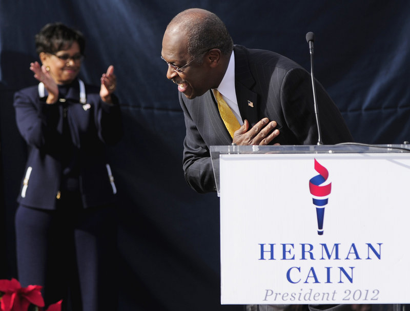 Republican presidential candidate Herman Cain bows and his wife, Gloria, applauds as Cain arrives on stage for his announcement Saturday in Atlanta, at what was to have been the opening of his national campaign headquarters.