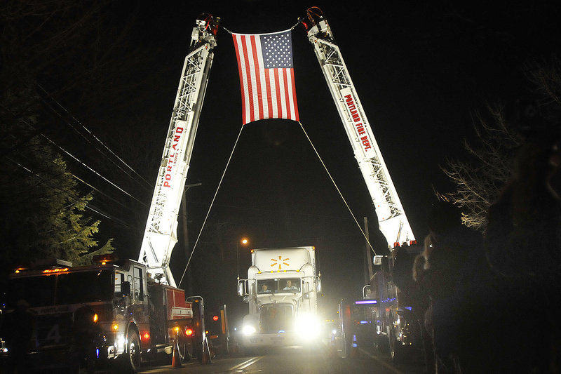 The convoy carrying wreaths from Harrington passes under an arch on Sunday outside Cheverus High School in Portland, where it stopped for a ceremony before continuing to Arlington National Ceremony. The wreaths will be laid on service members' graves.