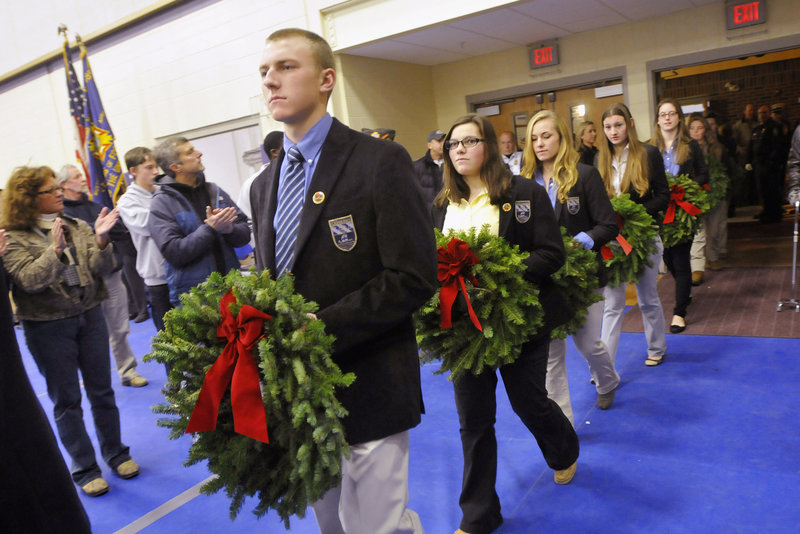 Cheverus students, from left, Spencer Amberson, Michelle Giordano and Aliza Hellier lead a procession into the gym during the Wreaths Across America salute.
