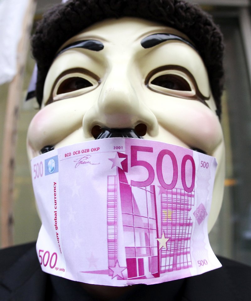 A Frankfurt Occupy activist wears an “occupy global currency” bill on his mask in front of the European Central Bank in Frankfurt, Germany, on Thursday. While Occupy groups were demanding changes in the bank’s lending priorities, EU officials were working to come up with a plan that would persuade the bank to do more to reinforce the euro.