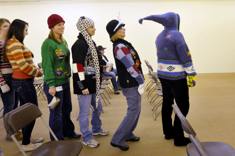 Roxanne Bennett of Kennebunk leans back to avoid getting poked by Brenda Mannino’s pointy hooded sweater as contestants in the Ugly Holiday Sweater Contest line up for the judges at the Wells Corner Shopping Center on Sunday. Behind Bennett are her daughters Joy and Brittney, followed by Courtney Goodwin and Marie Lawton of Chelmsford, Mass.