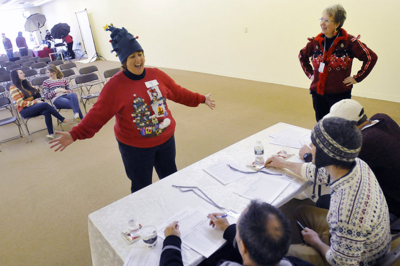 Tami Gower of Wells models her Christmas tree hat and sweater combination for the judges at the Ugly Holiday Sweater Contest on Sunday. At right is MJ Dillingham, organizer of the event, which raised funds for Goodwill Industries.
