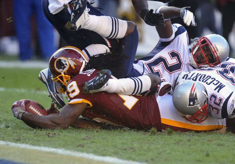 Donte Stallworth of the Redskins is brought down short of the goal line by Patriots defensive back Nate Jones and cornerback Devin McCourty.