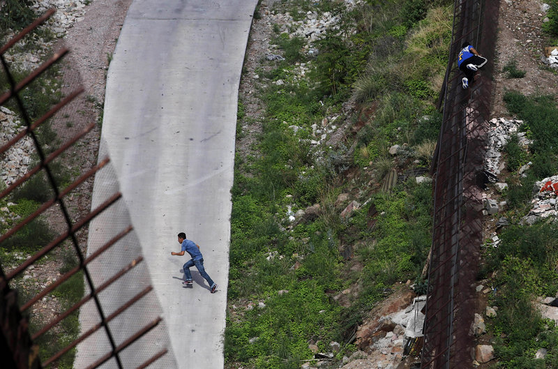 Two men illegally cross the border fence separating Nogales, Ariz., and Nogales, Mexico. The Supreme Court agreed Monday to review a federal appeals court ruling that blocked several provisions of Arizona’s controversial law.