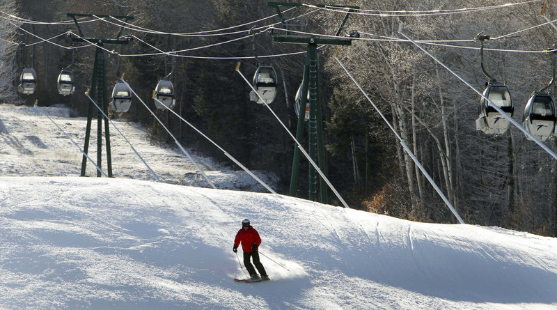 A lone skier uses an open trail at Loon Mountain ski area in Lincoln, N.H., on Monday while empty gondolas remain parked above.
