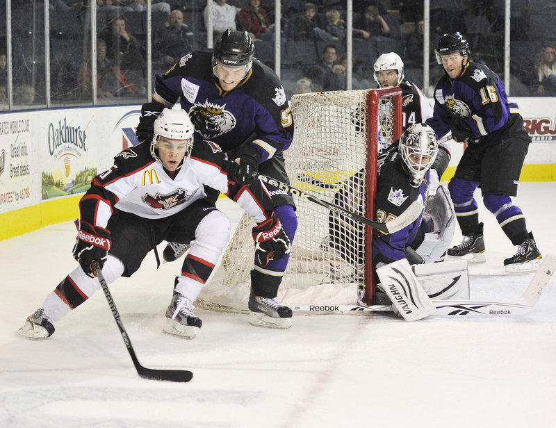 Marc-Antoine Pouliot of the Portland Pirates carries the puck around the net while being pursued by Jordan Hill of the Manchester Monarchs.