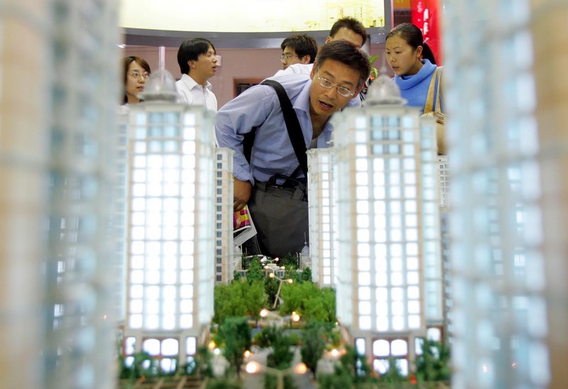 A man checks out a model of a planned housing complex at a real estate fair in Beijing. With average prices in the Shanghai area down about 40 percent from their peak in mid-2009, real estate buyers are more cautious.