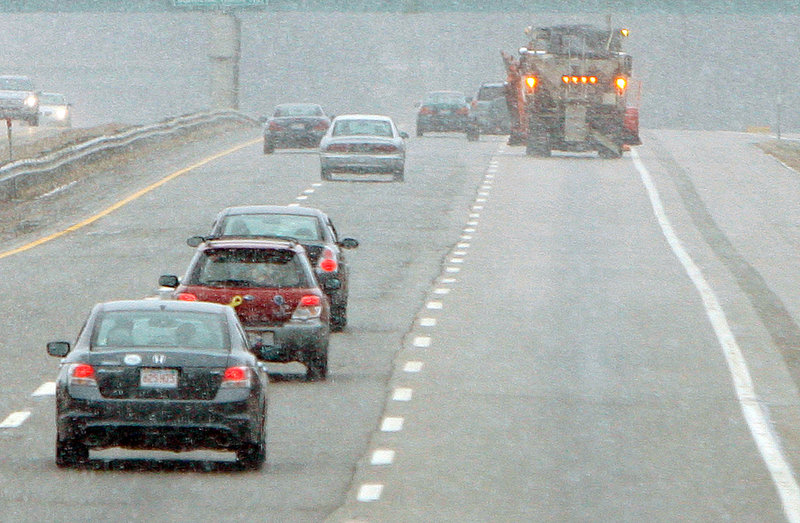 A plow truck patrols the northbound lane of the Maine Turnpike in Biddeford during a heavy snow squall Saturday. Snow and freezing temperatures caused numerous fender benders.