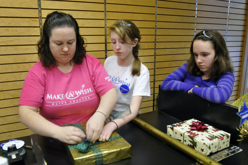 Sabrina Craig of Auburn wraps a gift at the Maine Mall on Sunday to raise funds for Make-A-Wish with her niece Mariah St. Pierre, 14, of Fayette and daughter Hailey Sontag, 11.