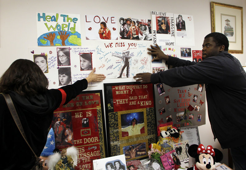 Michael Jackson fans Kim Lemieux, left, and Michael Craig hang a poster at a memorial to Jackson, during a private preview Dec. 11 at Julien’s Auctions in Beverly Hills, Calif., of the contents of the home where the singer and his children lived at the time of his death.