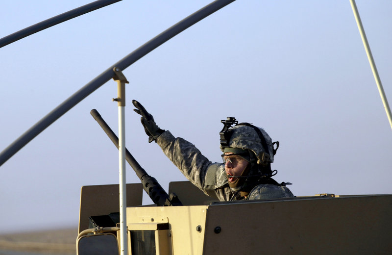 A soldier gestures from the gun turret of the last vehicle in a convoy of the U.S. Army’s 3rd Brigade, 1st Cavalry Division, as it crosses the border from Iraq into Kuwait on Sunday. The brigade’s special troops battalion were the last American soldiers to leave Iraq.