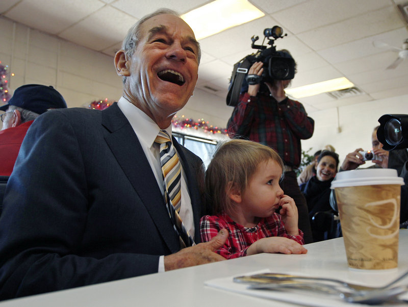 Rep. Ron Paul, R-Texas, sits with Elizabeth Rose Chamberlain, 3, of Epping, N.H., while campaigning at the Early Bird Cafe in Plaistow on Tuesday. The presidential candidate’s fiscal conservatism has gained him supporters.