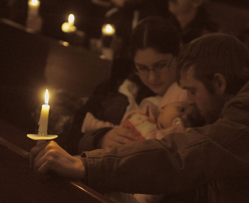 Ken Brown and Hannah Letourneau hold their daughter Mackenzie Brown as prayers are offered Wednesday night during a vigil for Ayla Reynolds at a Waterville church.