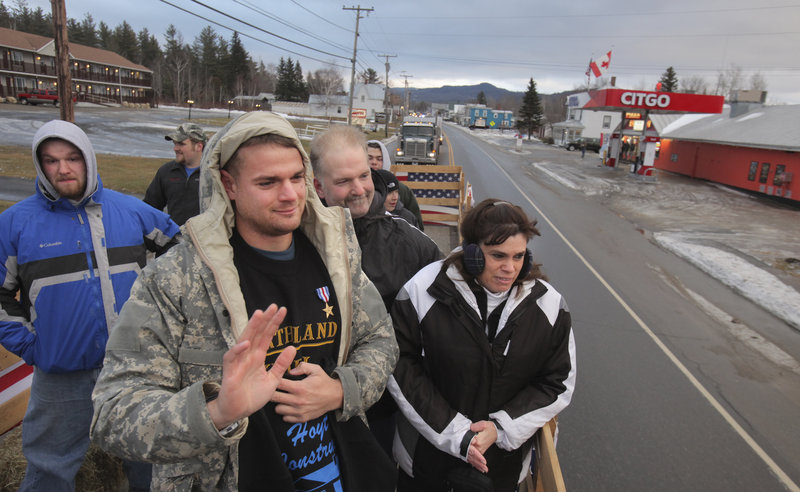 Sgt. Timothy Gilboe waves to well-wishers as he rides in a flatbed truck in his welcome-home parade in Jackman on Thursday. He’s accompanied by his parents, Steve and Deanna, and a brother, Ben, left.