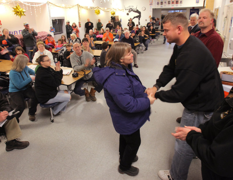 Kathleen MacKenzie, Jackman’s town manager, shakes hands with Sgt. Timothy Gilboe at a reception after a parade honoring Gilboe in Jackman on Thursday.