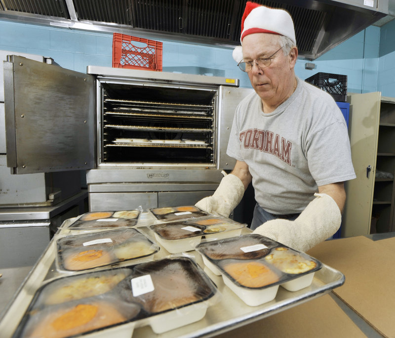 Tom O’Connor of Portland pulls trays of prepared meals from the oven where they were heated before being delivered Sunday.