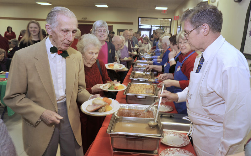 Bill Tolman, left, makes his way through the serving line at the annual holiday dinner hosted by Westbrook-Warren Congregational Church. About 300 people were fed this year.