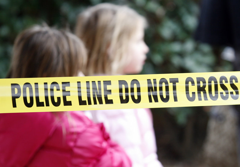 Two young girls walk by police tape that stretches through a Grapevine, Texas, apartment complex where police found seven people dead in an apartment on Christmas Day. Police believe the victims, four women and three men, were related.