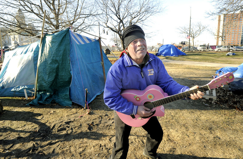 Bobby Davis, 51, plays his pink guitar Thursday at the park. “It’s tough to survive,” the Falmouth man said.
