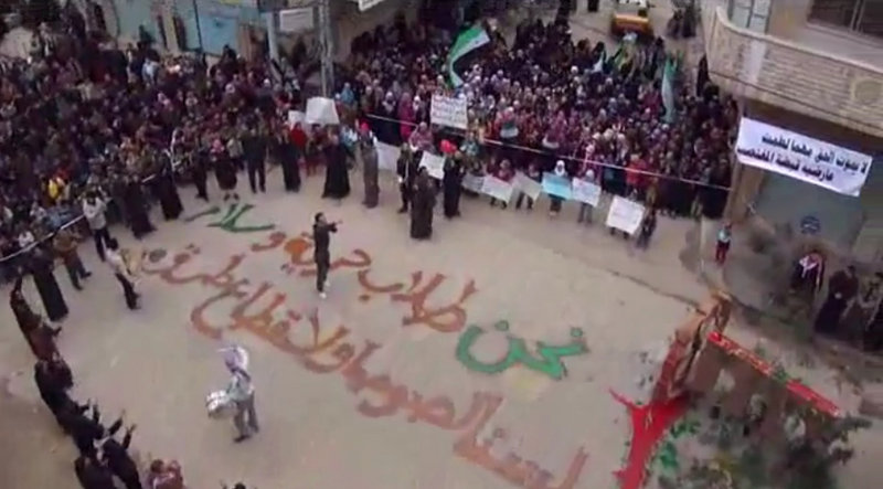 An amateur video shot Friday shows protesters gathered in Homs, Syria. The writing on the ground, in Arabic, reads : “We are those who seek freedom and peace. We are not thieves or outlaws.”