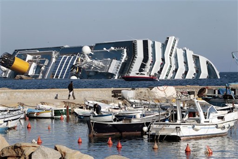 The luxury cruise ship Costa Concordia leans on its starboard side as seen from the Giglio harbor. The luxury cruise ship ran aground off the coast of Tuscany, sending water pouring in through a 160-foot (50-meter) gash in the hull and forcing the evacuation of some 4,200 people from the listing vessel early Saturday. (AP Photo/Gregorio Borgia)