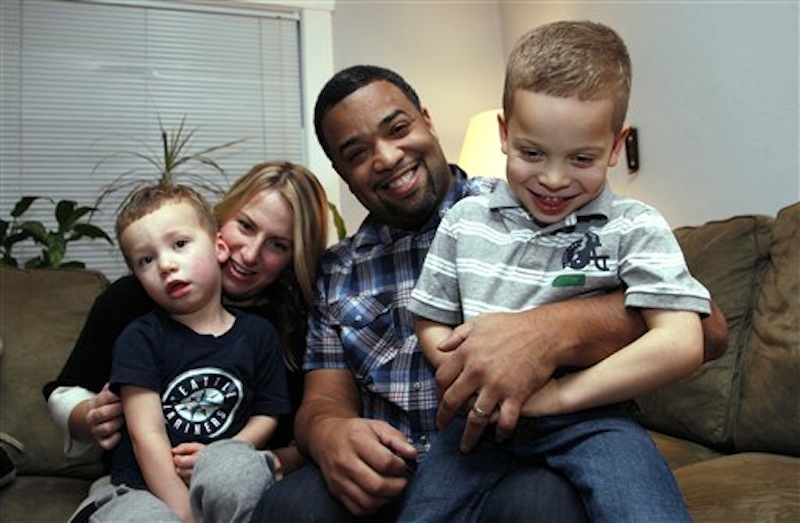 In this Dec. 27 photo, Damon Brown sits with his wife, Bethany, as they hold their sons Theo, 3, left, and Julian, 5, at their home in Seattle. Damon Brown found a kidney on Facebook after telling his story on a special page the Seattle dad created under the name, "Damon Kidney". (AP Photo/Elaine Thompson)