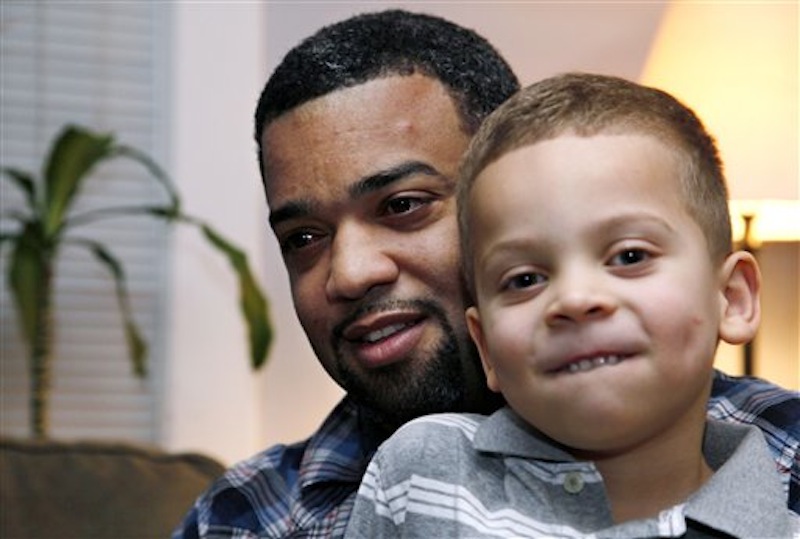 In this Dec. 27, 2011, Damon Brown sits with his son Julian, 5, at their home in Seattle. (AP Photo/Elaine Thompson)