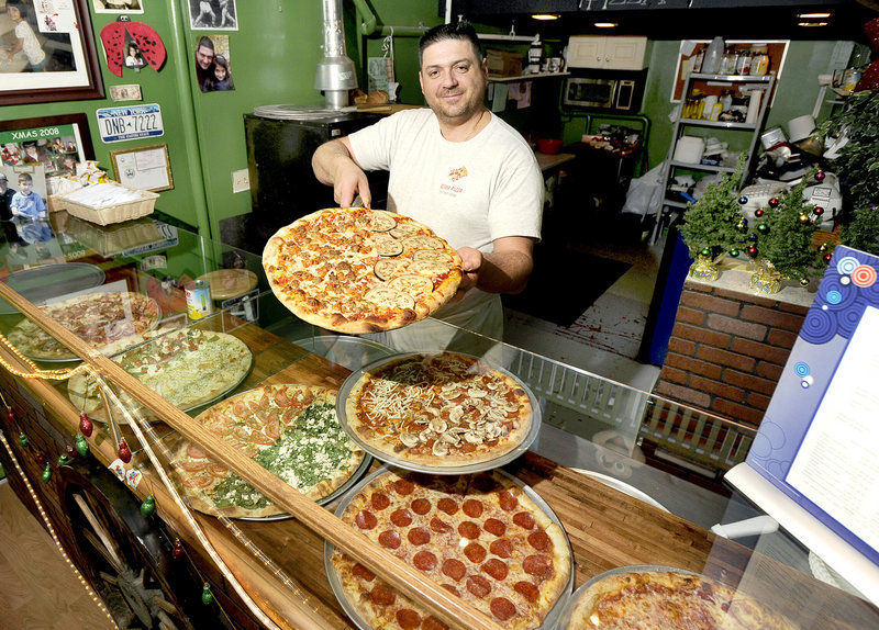 Owner Luca Pizzuti shows off a meat lover and eggplant rollatini pizza at Roma Pizza in Portland.